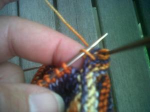 Closing the gap after completing the first round of the ankle by knitting the stitch BELOW the the last stitch on needle #4 together with the first stitch on needle #1. stitch on